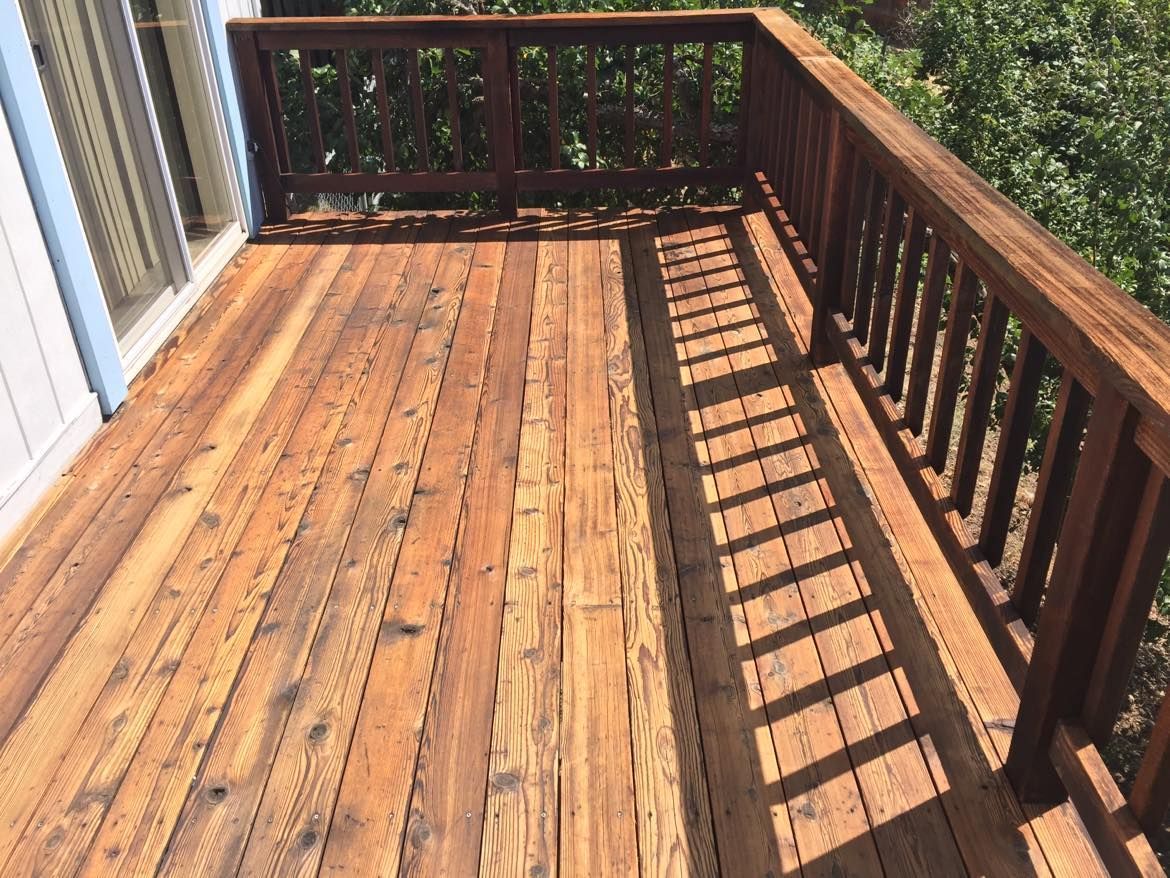 Wooden deck with railing. Shadows cast across the boards.