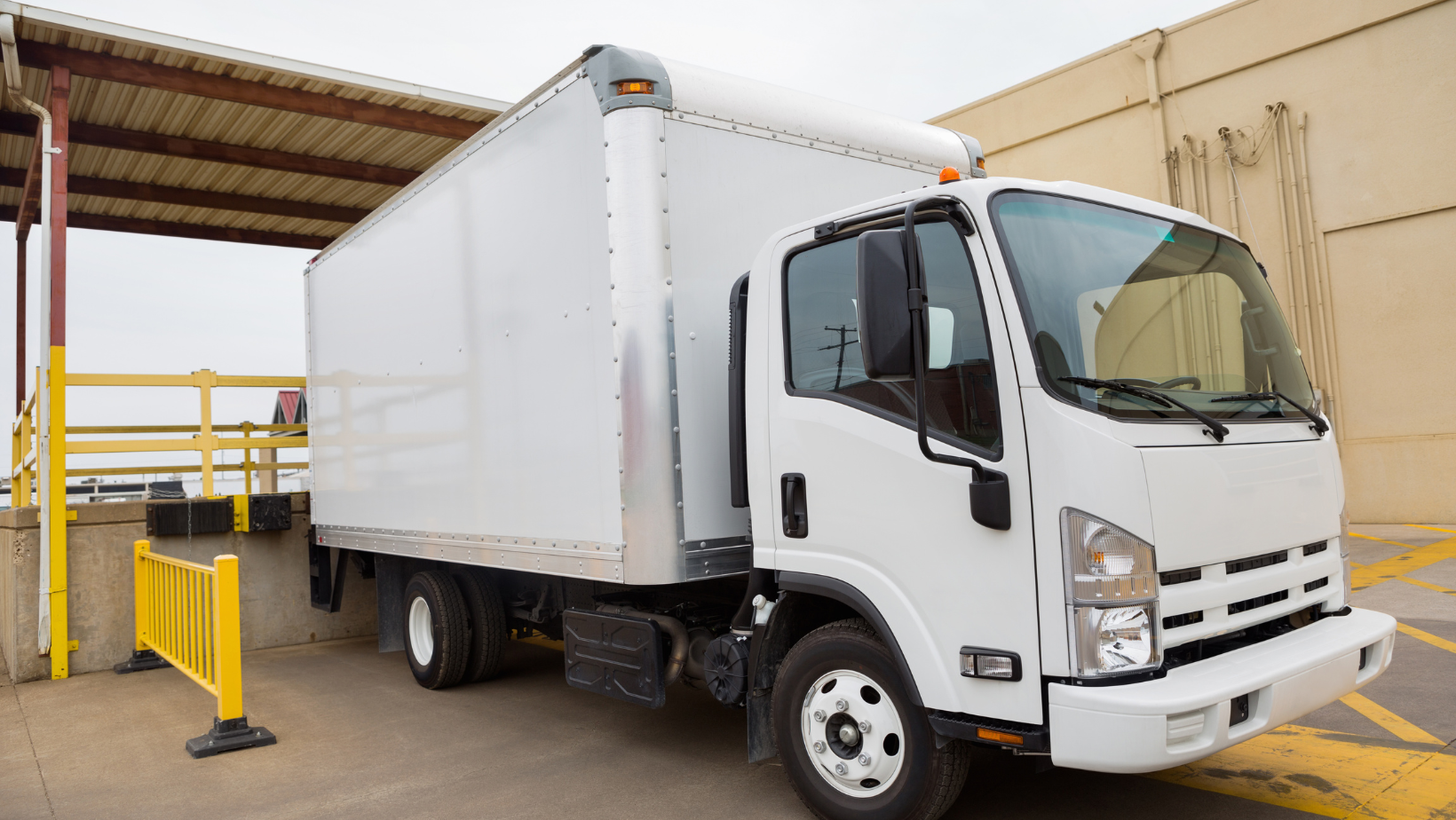 A white truck is parked in a parking lot next to a building.