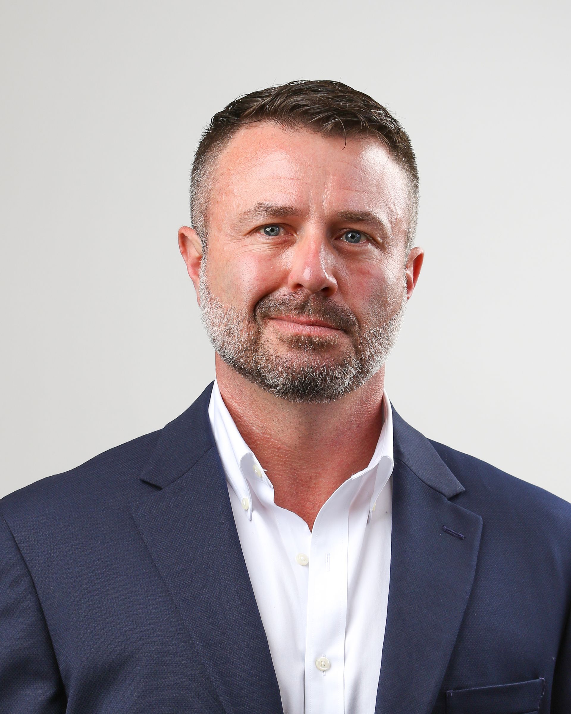 A man with a beard is wearing a blue suit and white shirt.
