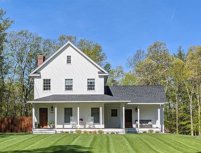 a large white house with a porch and a lush green lawn in front of it .