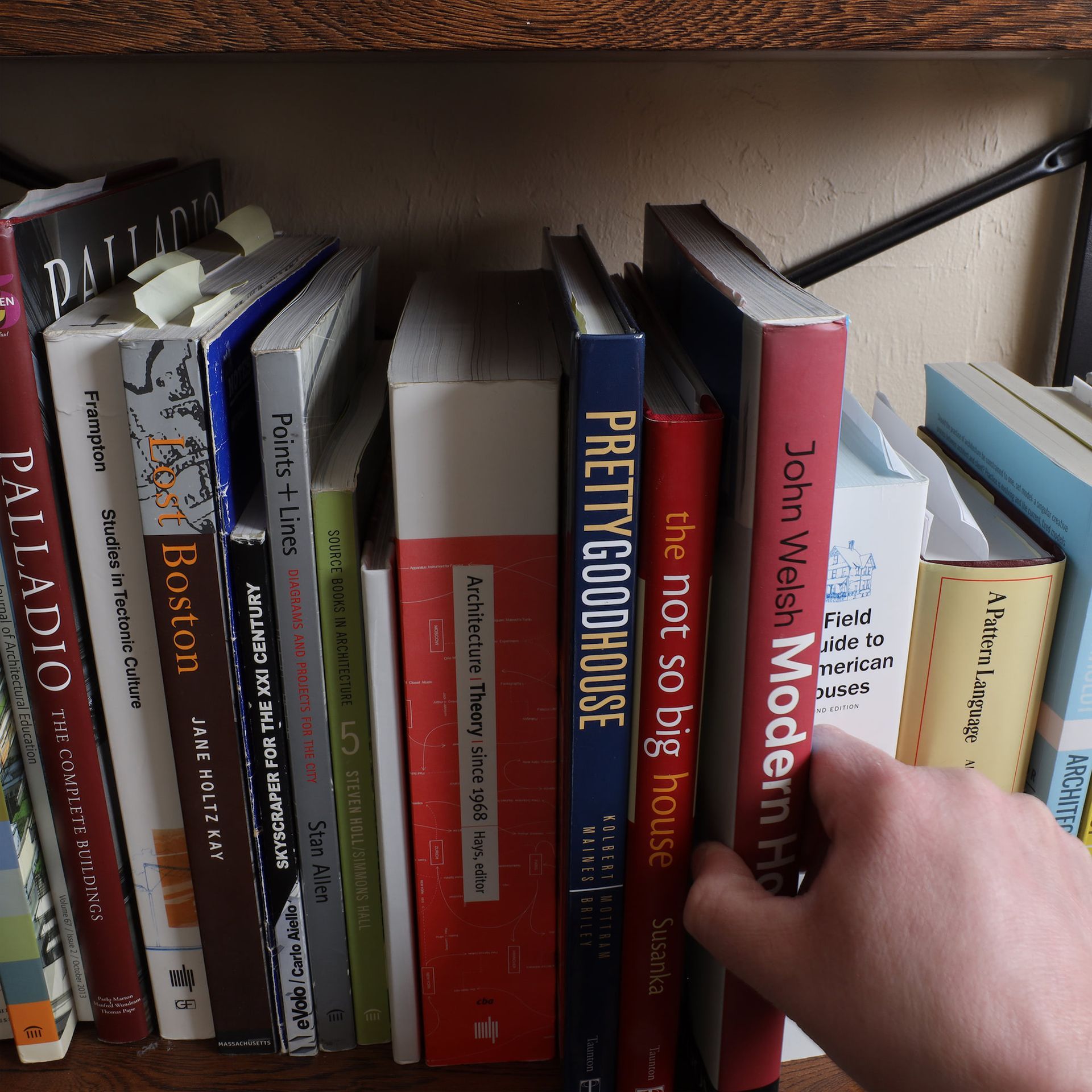 a hand reaches for a book titled pretty good house
