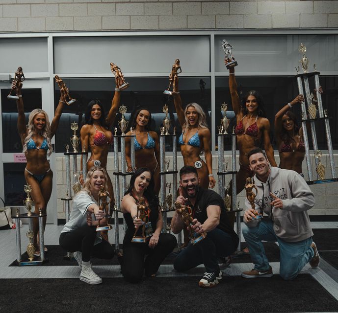 A group of people posing for a picture holding trophies