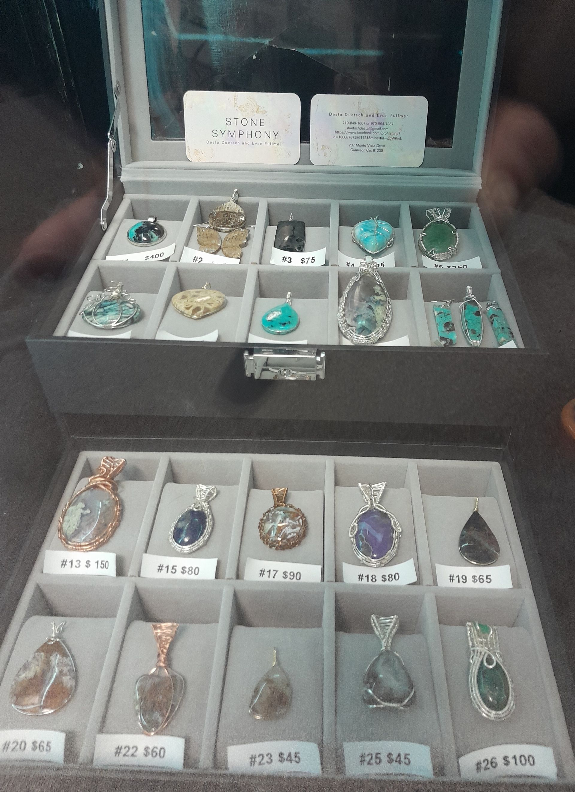 A display case filled with a variety of pendants and earrings