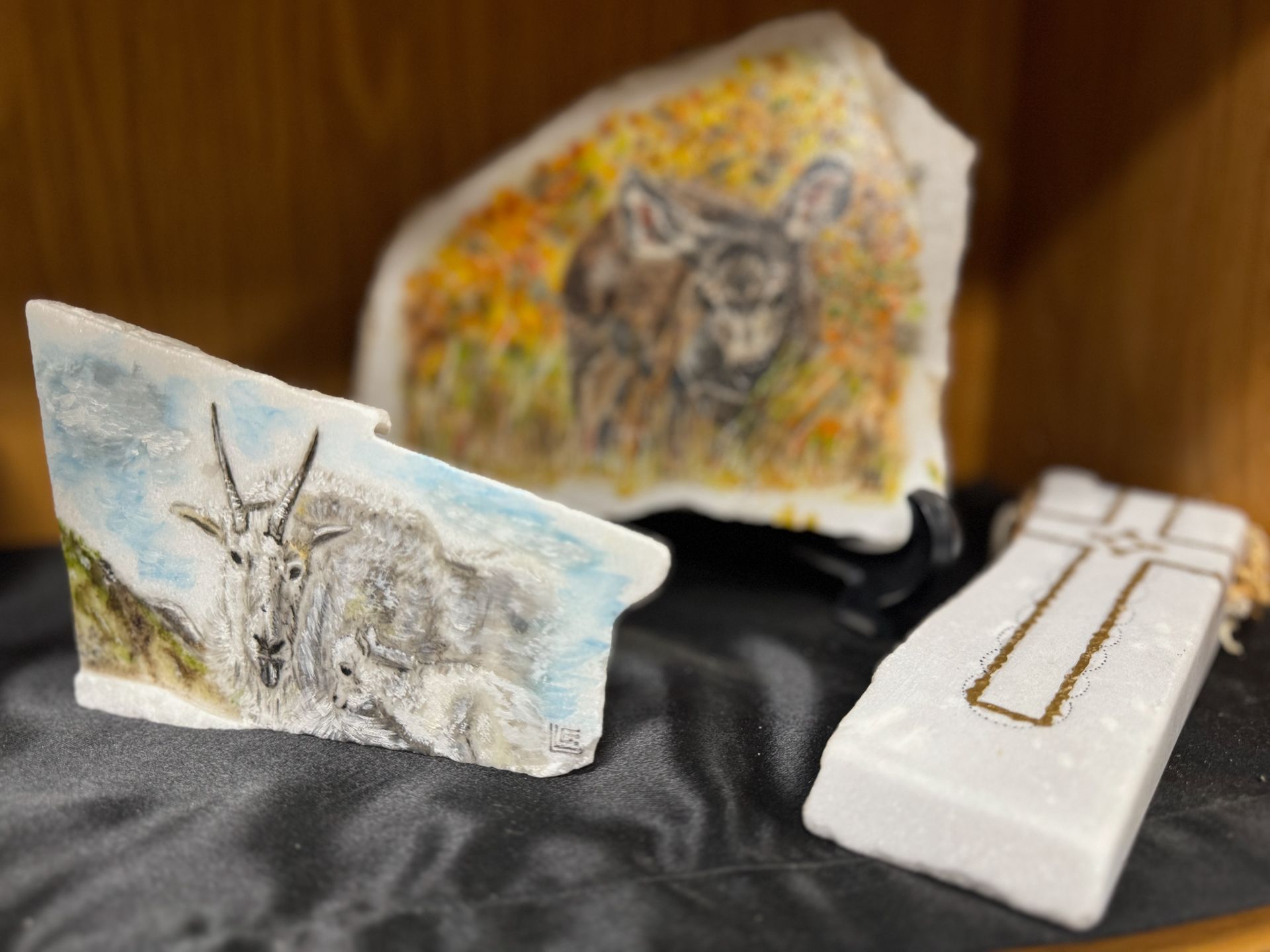 A painting of a sheep and a painting of a bear are on a table.