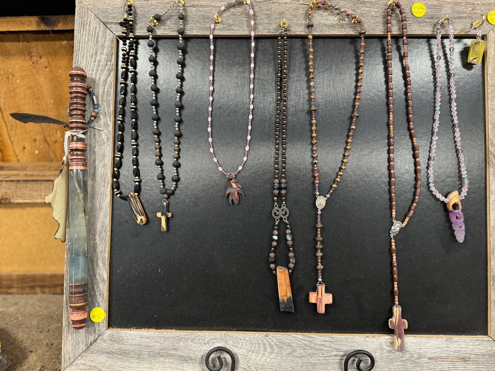 A bunch of necklaces are hanging on a black board.