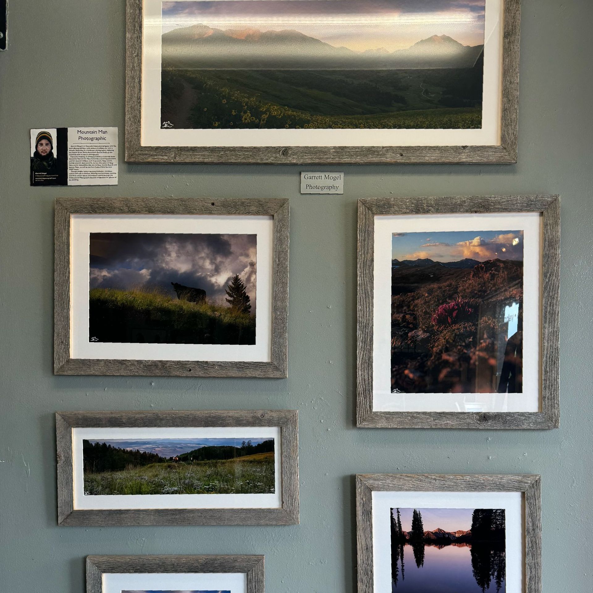 Several framed pictures are hanging on a wall including one of a landscape