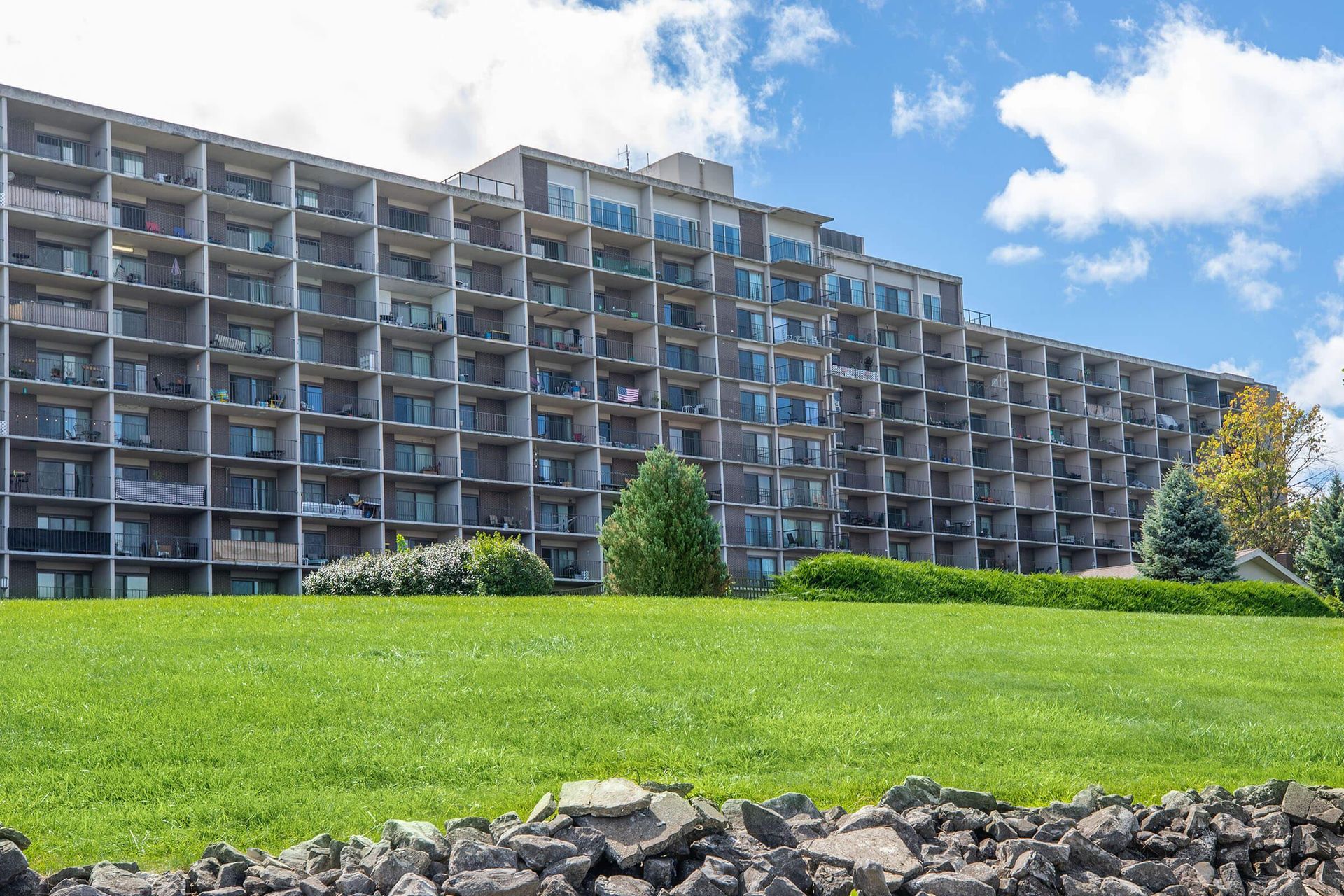 Large apartment building behind a green lawn under a partly cloudy blue sky