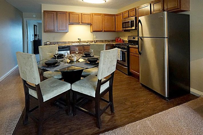 Modern kitchen with wooden cabinets, stainless steel fridge, and a dining table set for a meal