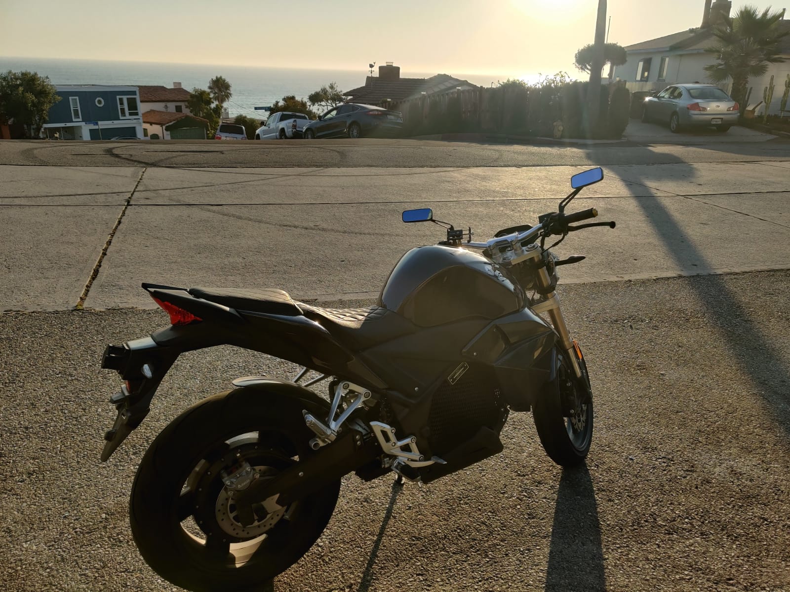 A black electric motorcycle is parked on the side of the road. Urban Classic 2021 