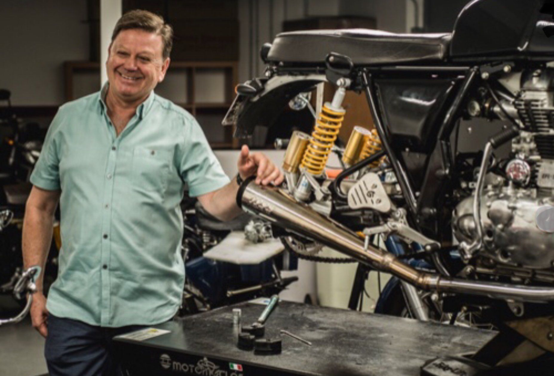 A man is standing next to a motorcycle in a garage.