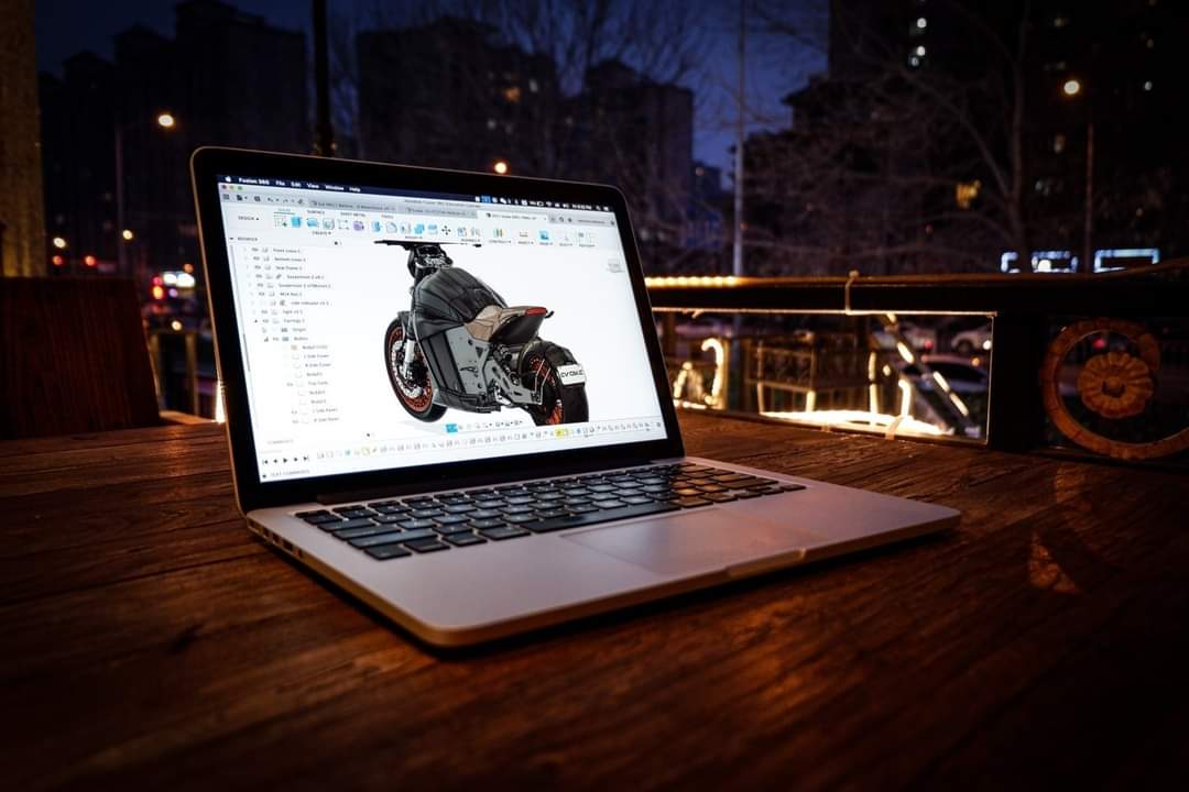 A laptop computer is sitting on a wooden table with a picture of a motorcycle on the screen.