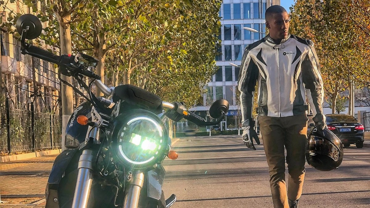 A man is walking down a street next to an electric motorcycle. Chicago, USA 2023 Urban Classic