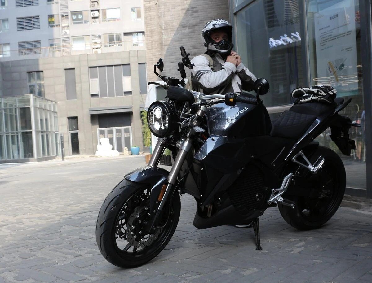 A man wearing a helmet is sitting on a black electric motorcycle in Beijing, China 2019