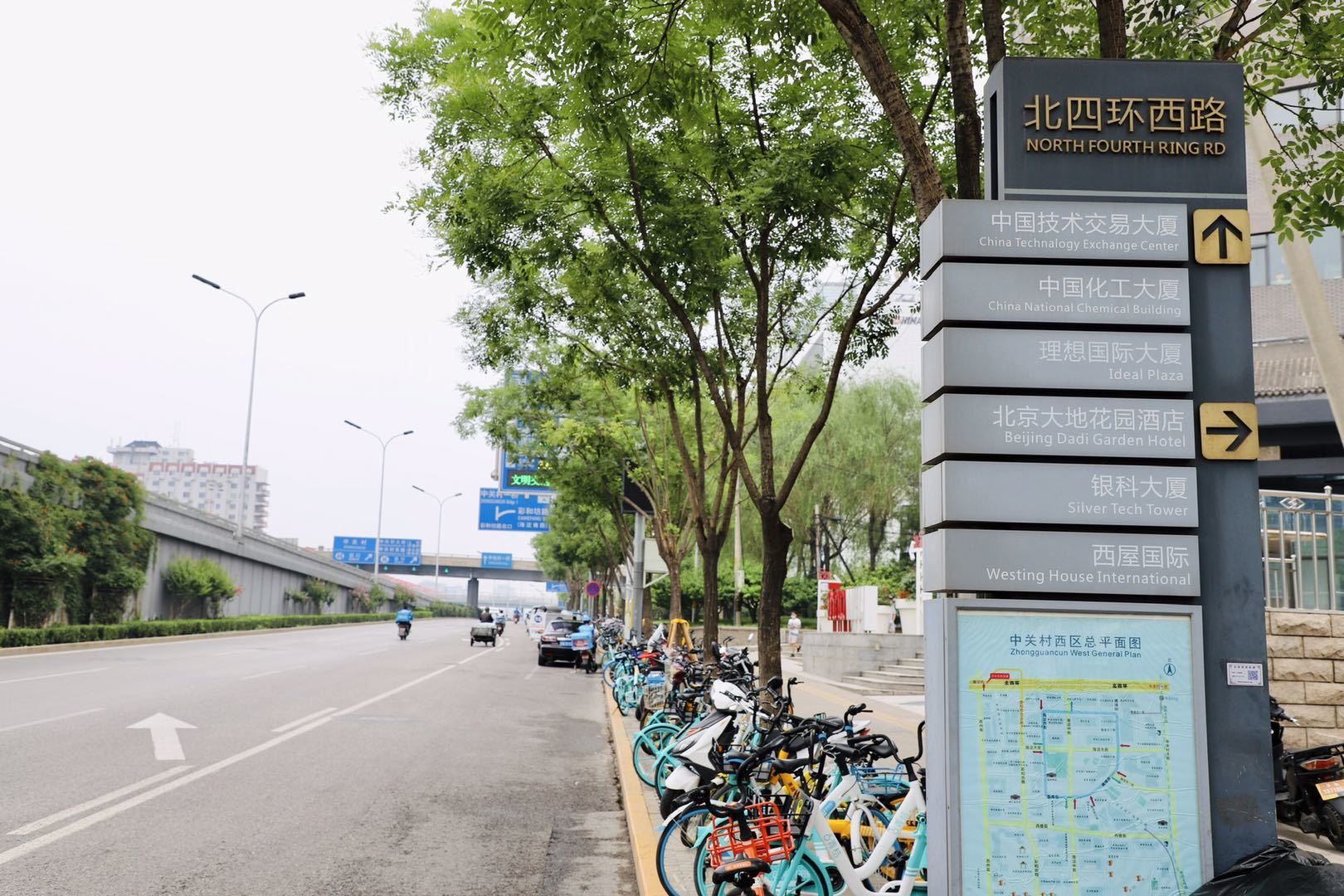 A row of bicycles are parked on the side of the road next to a sign.