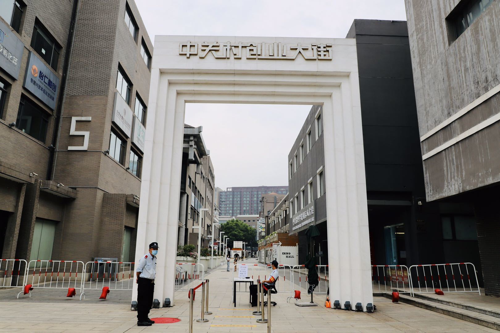 A man in a mask is standing in front of a building with chinese writing on it.