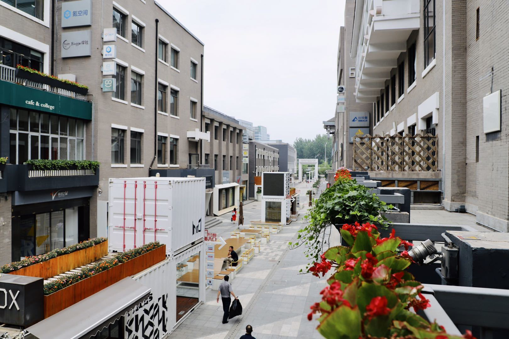 A man is walking down a narrow street between two buildings.