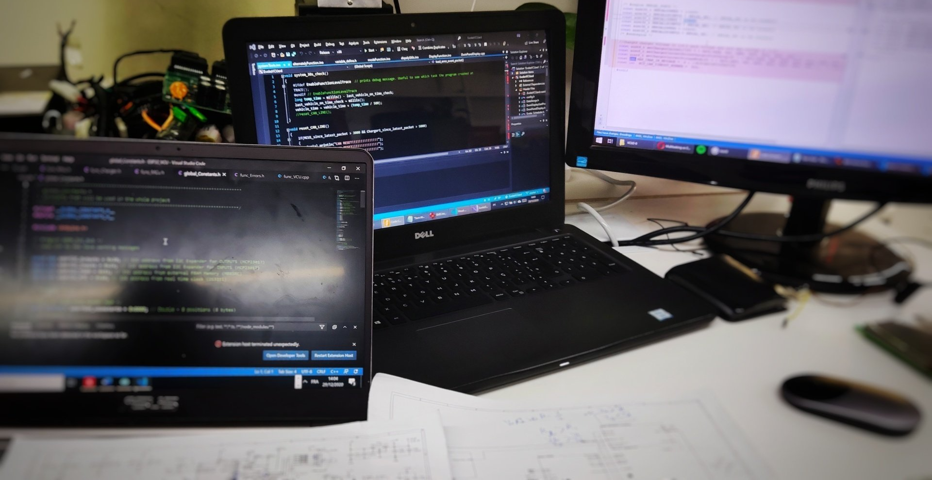 A laptop is open on a desk next to a monitor at an Evoke Motorcycles office