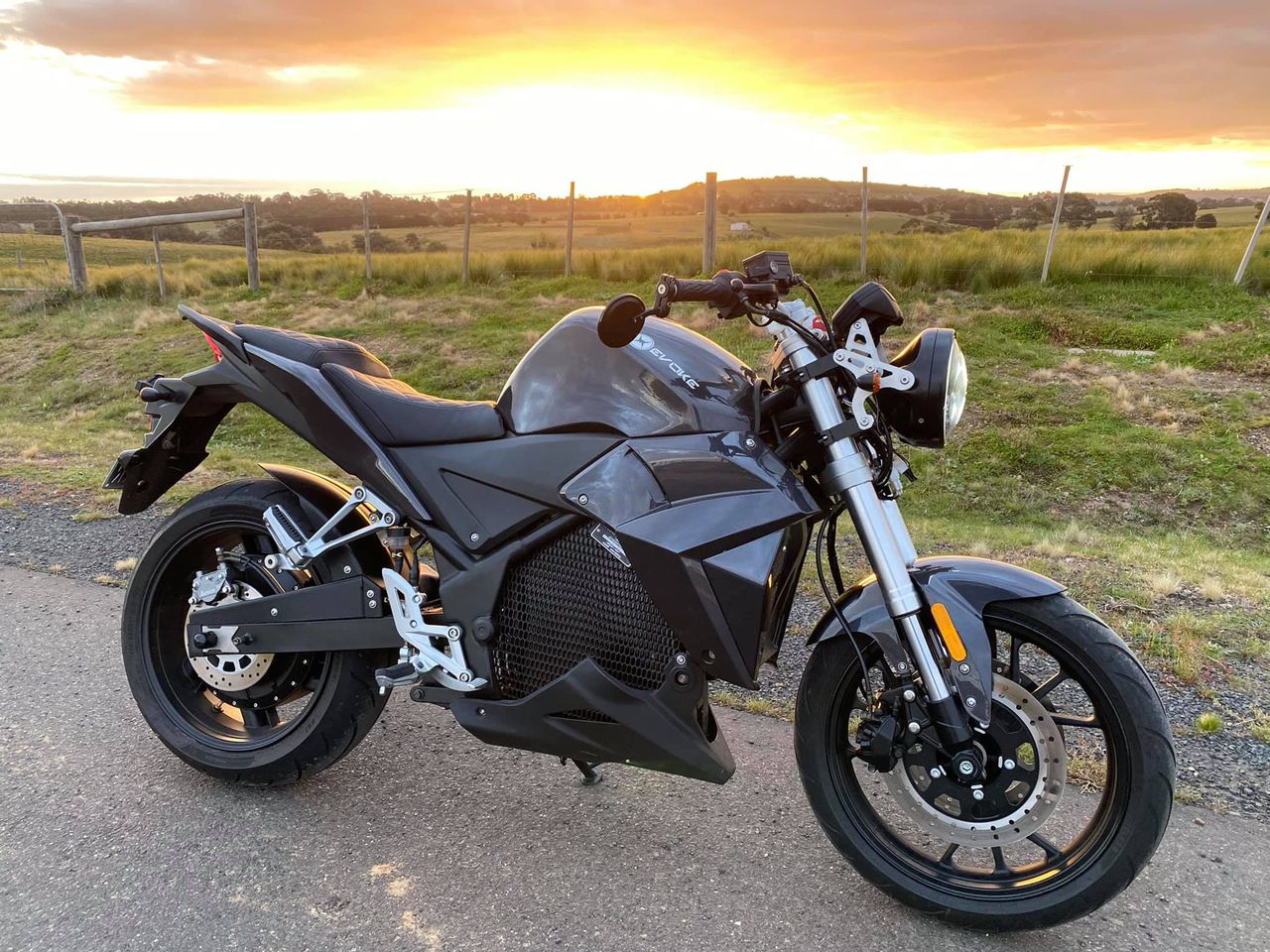 Urban Classic in black, an electric motorcycle is parked on the side of the road at sunset in Perth, Australia