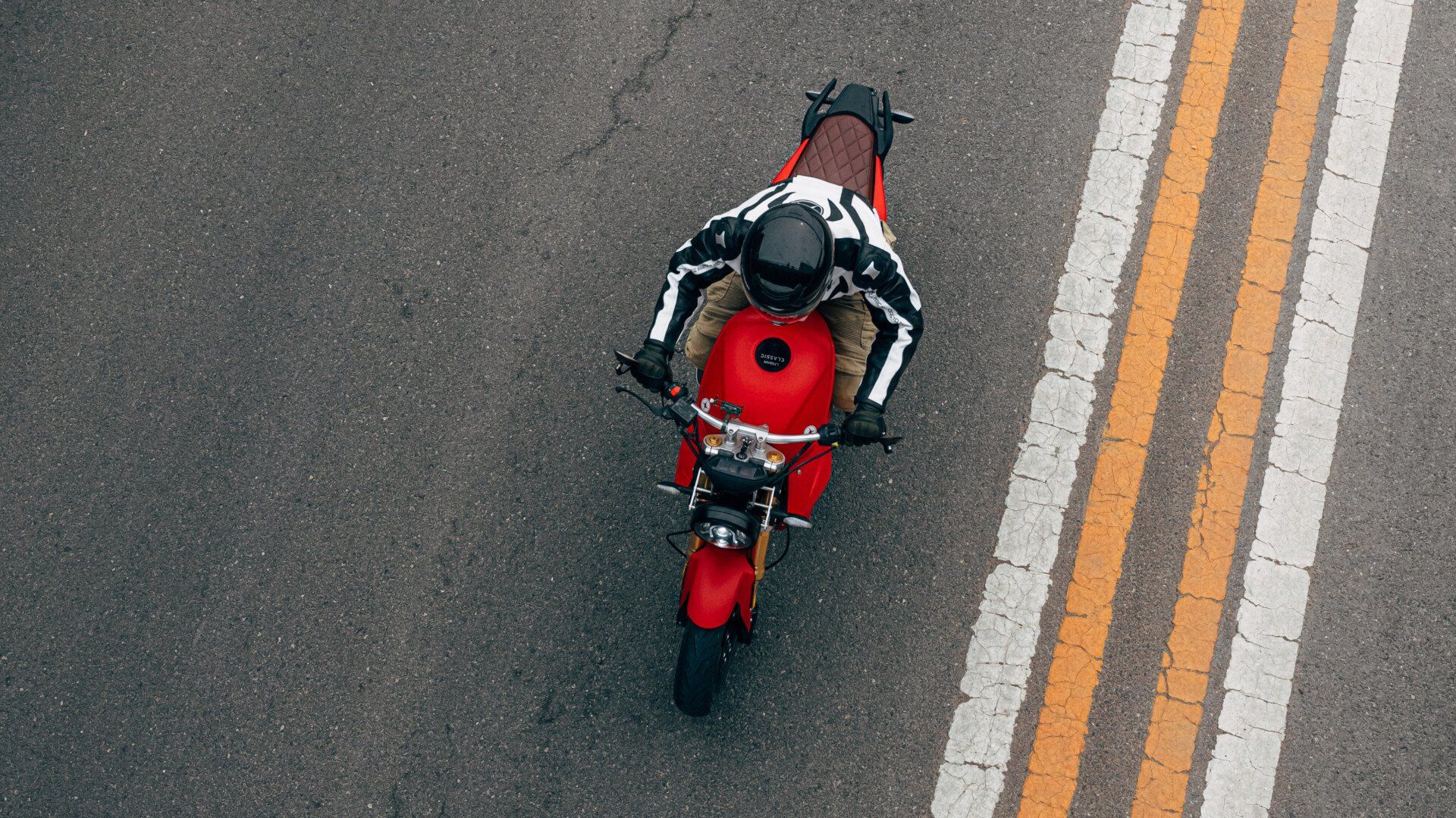 Nathan Siy is riding a red Urban Classic electric motorcycle down a street.