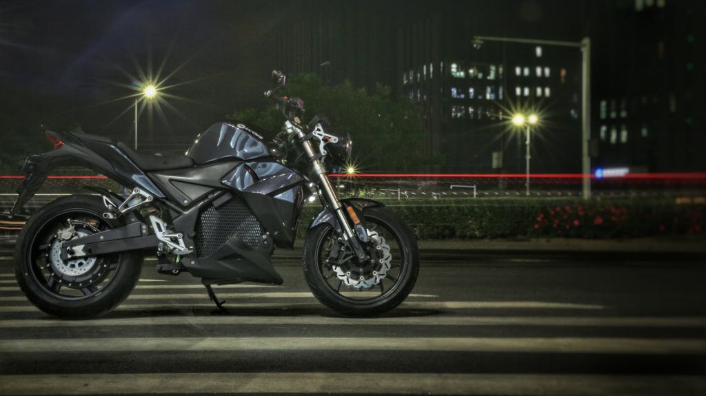 An Urban Classic electric motorcycle is parked on the side of the road at night.
