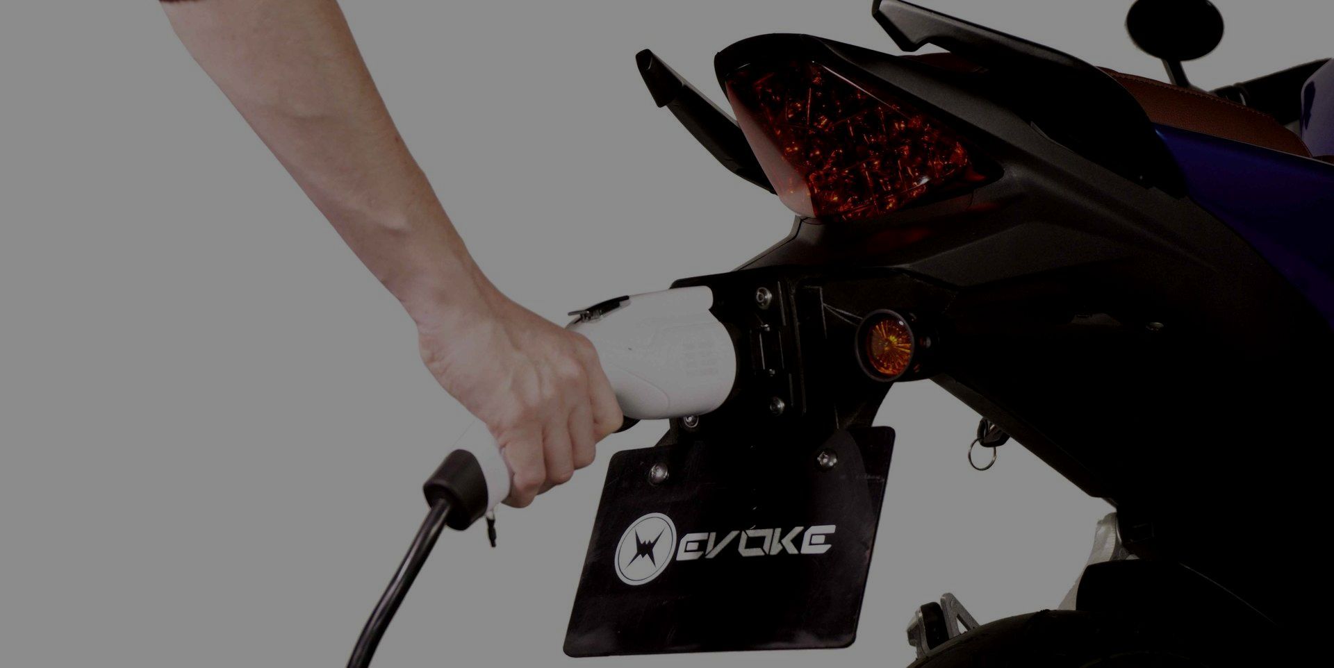 A person is charging an electric scooter with a charger.