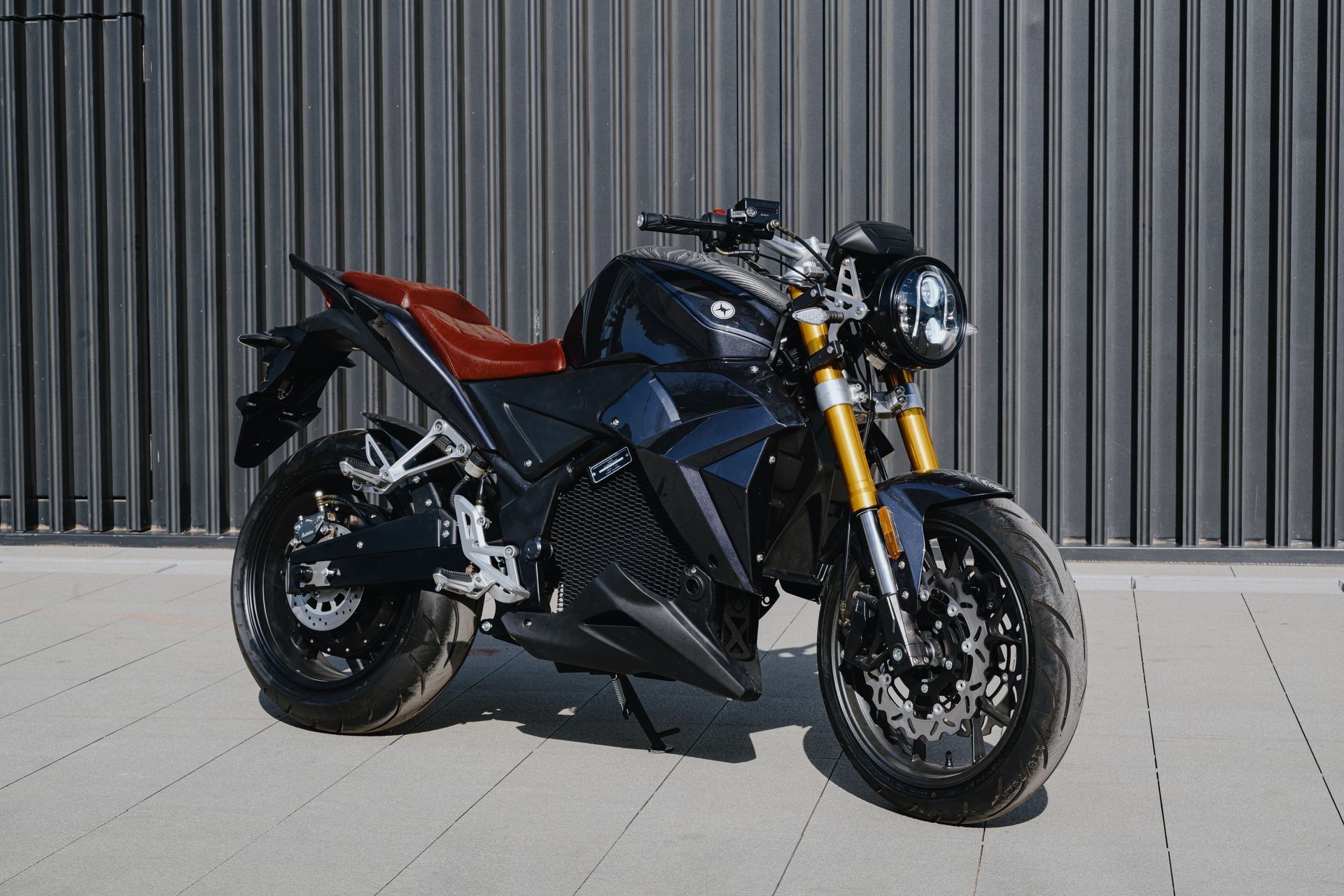 A black electric motorcycle by evoke_motorcycles is parked on a sidewalk in front of a building.