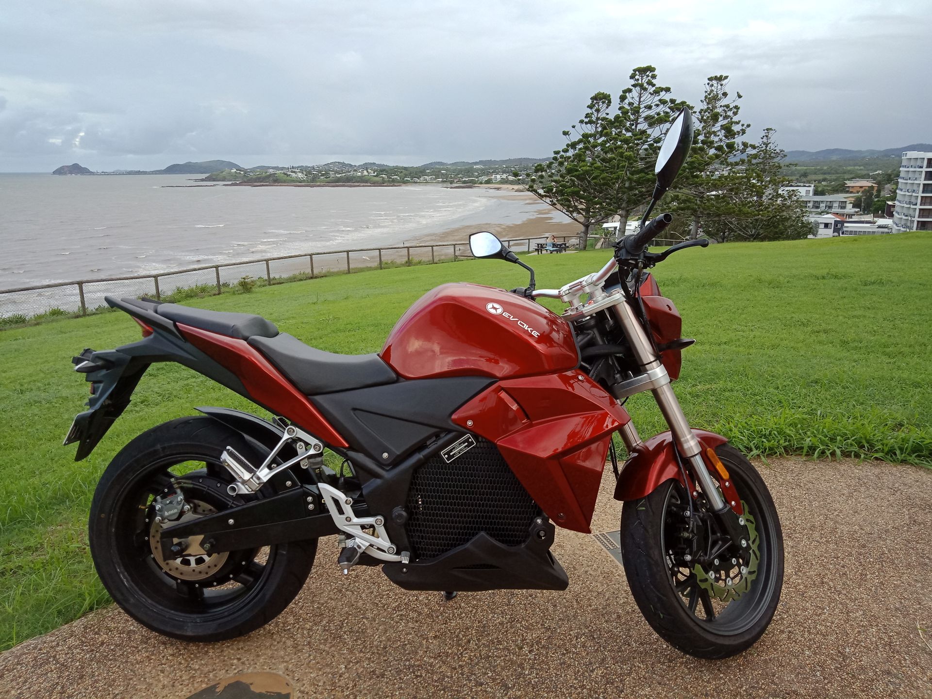 A red motorcycle is parked in front of a beach