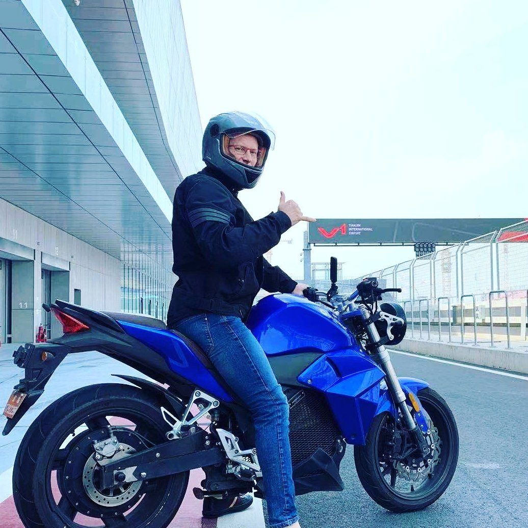 A man wearing a helmet is sitting on a blue electric motorcycle. Urban Classic 2022