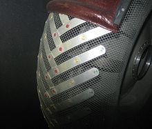 A close up of a metal object with a wooden handle on a black background.