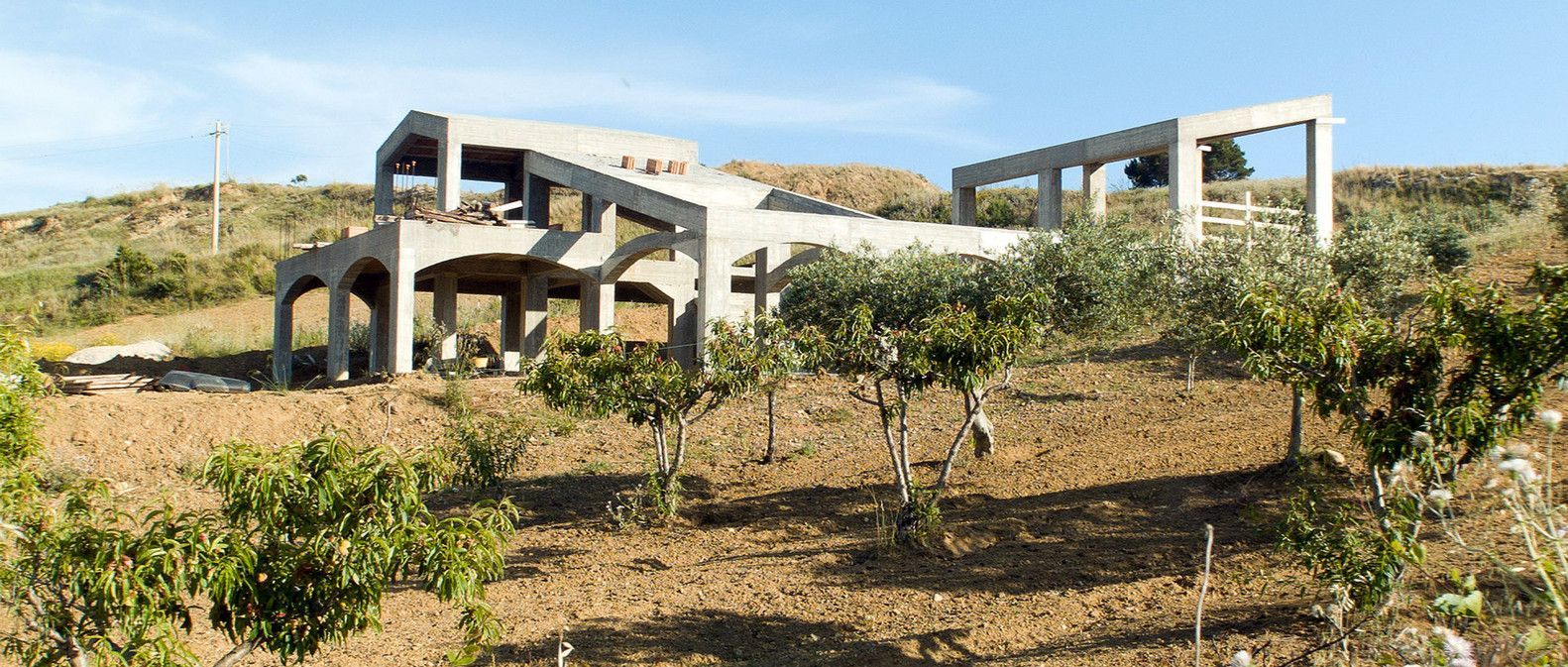 A large house is sitting on top of a hill surrounded by trees.