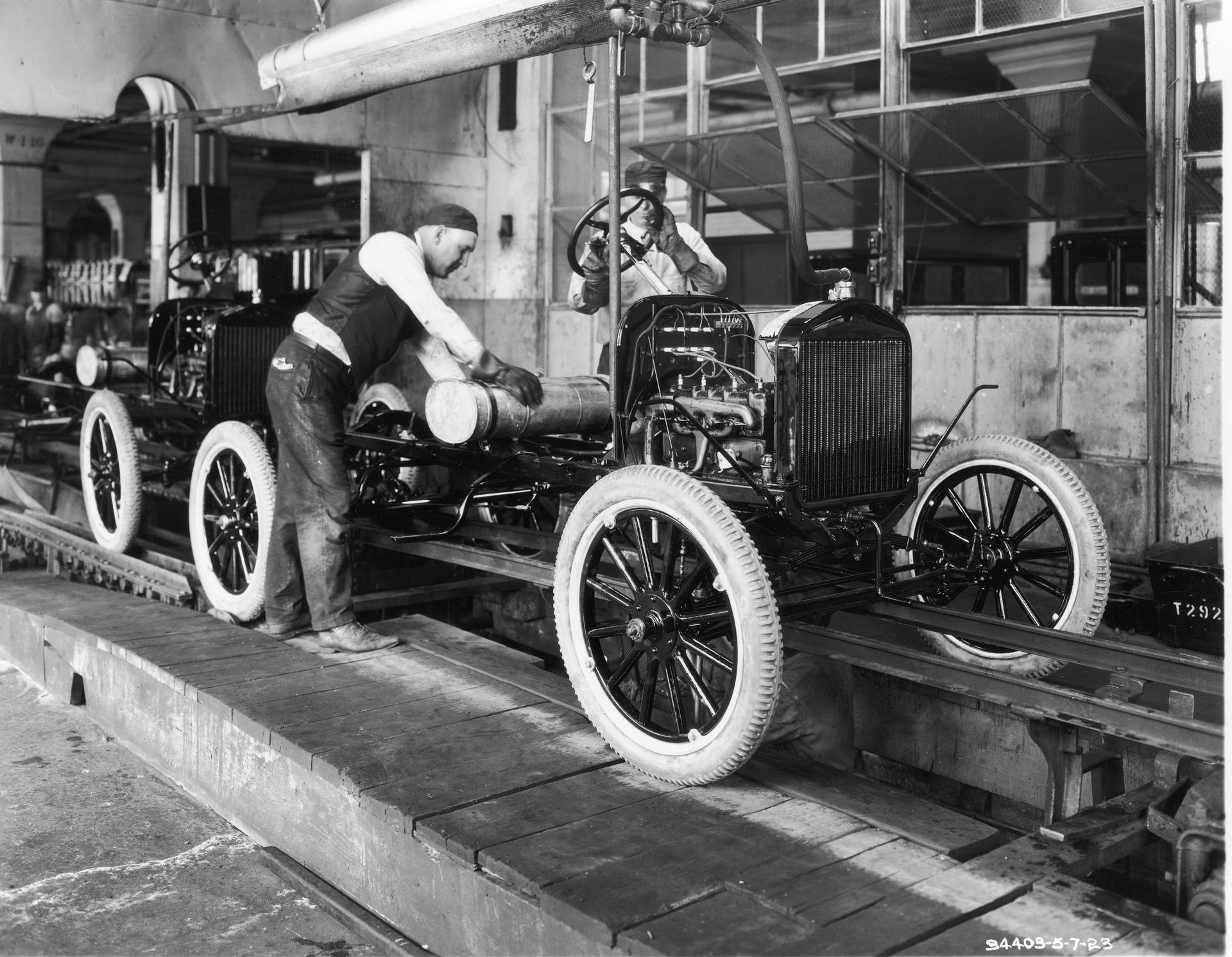A black and white photo of a man working on a car