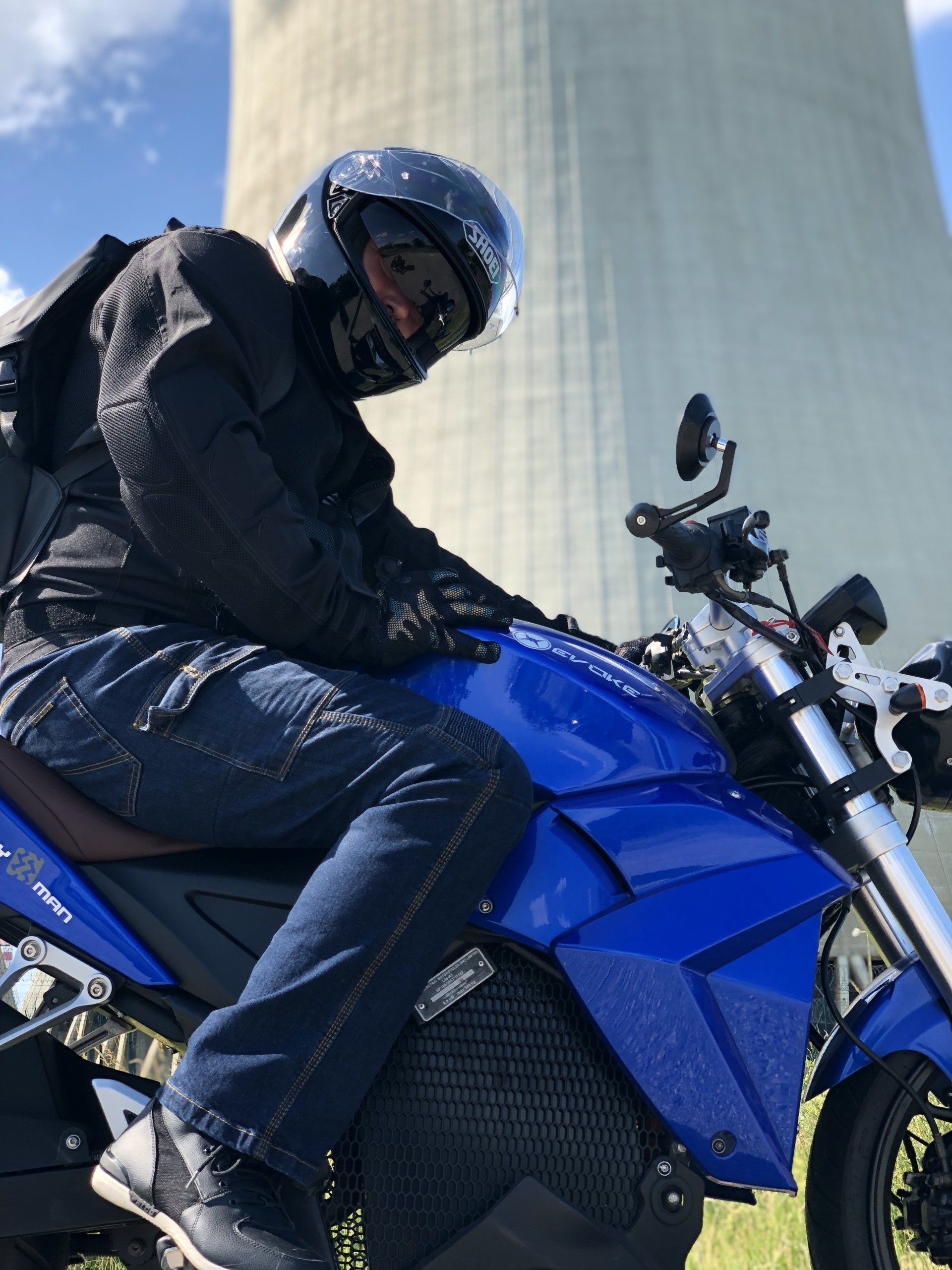 A man wearing a helmet is sitting on a blue electric motorcycle. Urban Classic 2019, Prague, Czech Republic