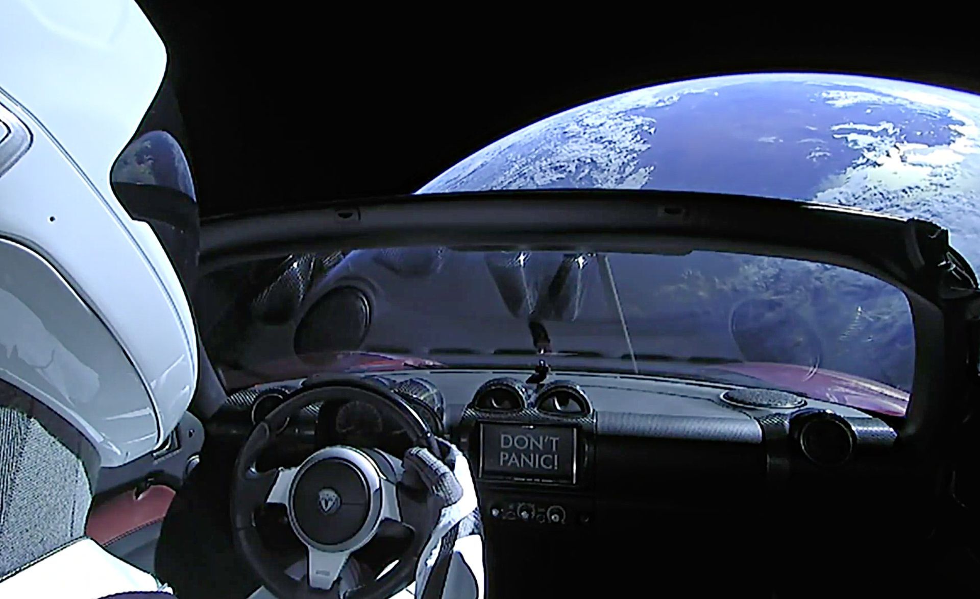A tesla car is flying in space with the earth in the background