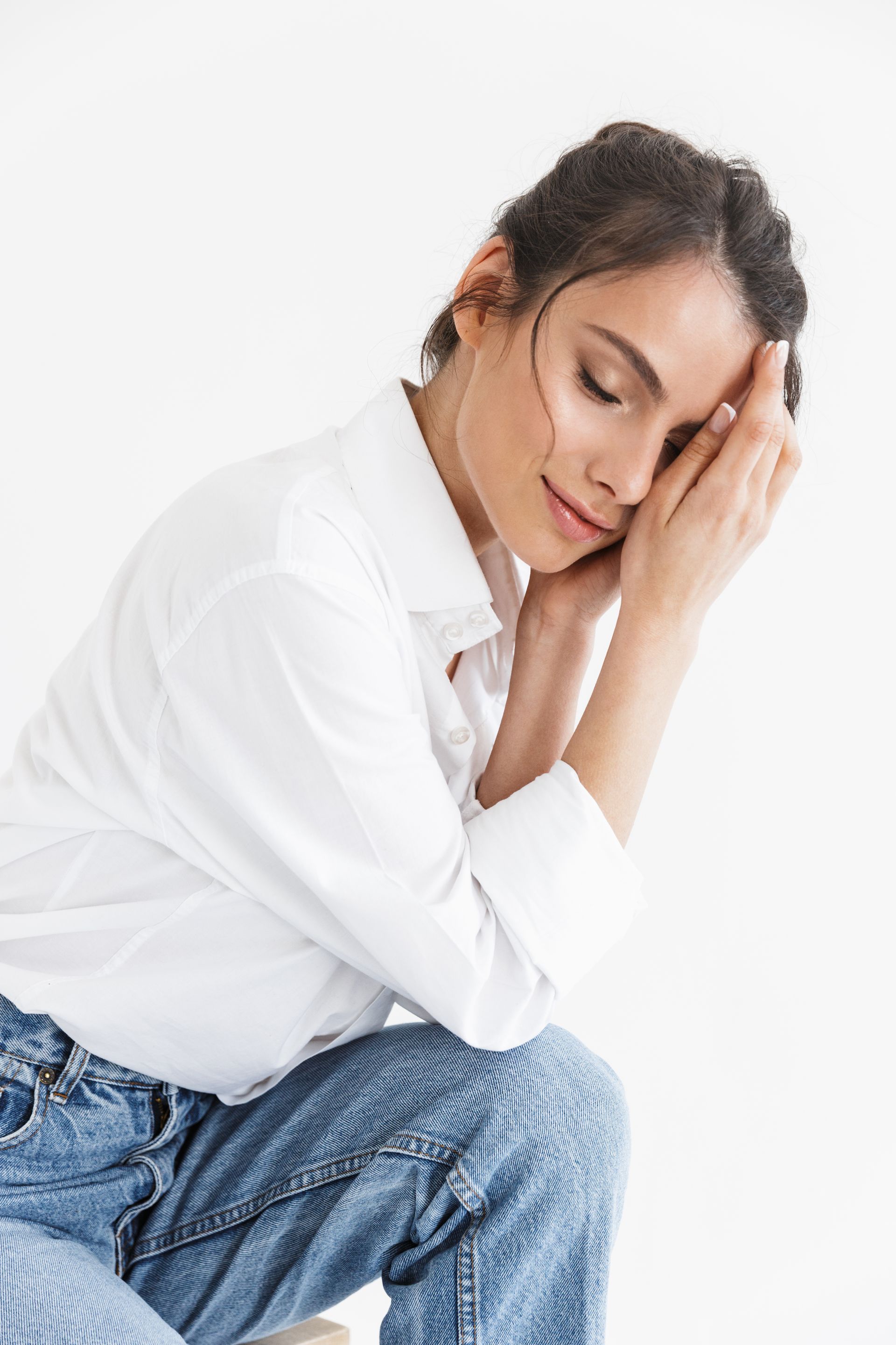 a woman in a tan sweater is covering her face with her hand