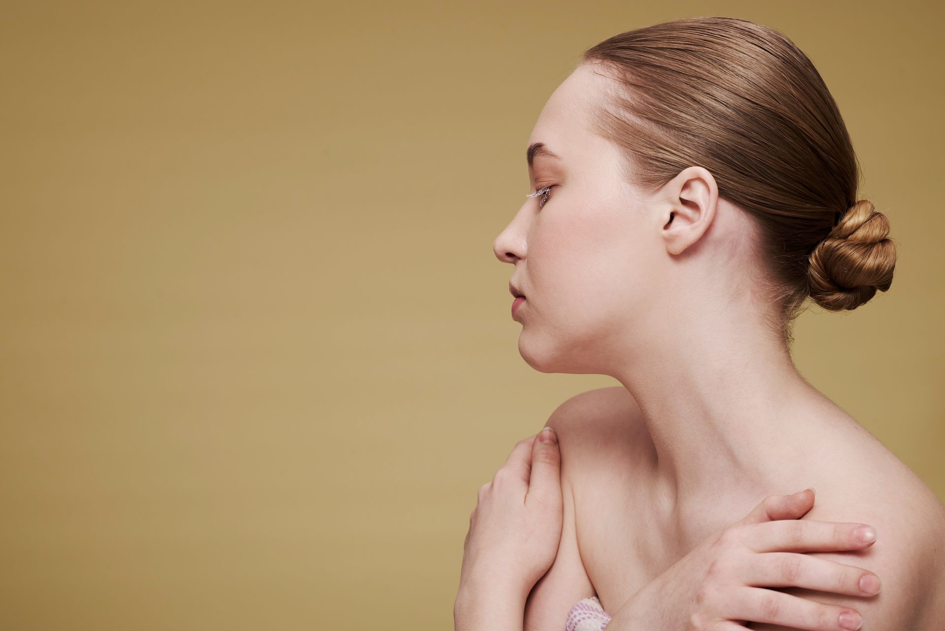 a woman with her hair in a bun is touching her shoulder