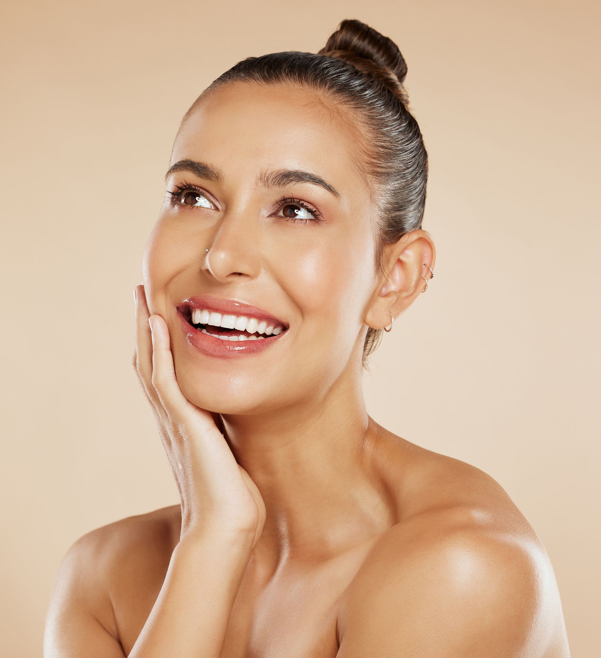 a woman with her hair in a bun is smiling and touching her face
