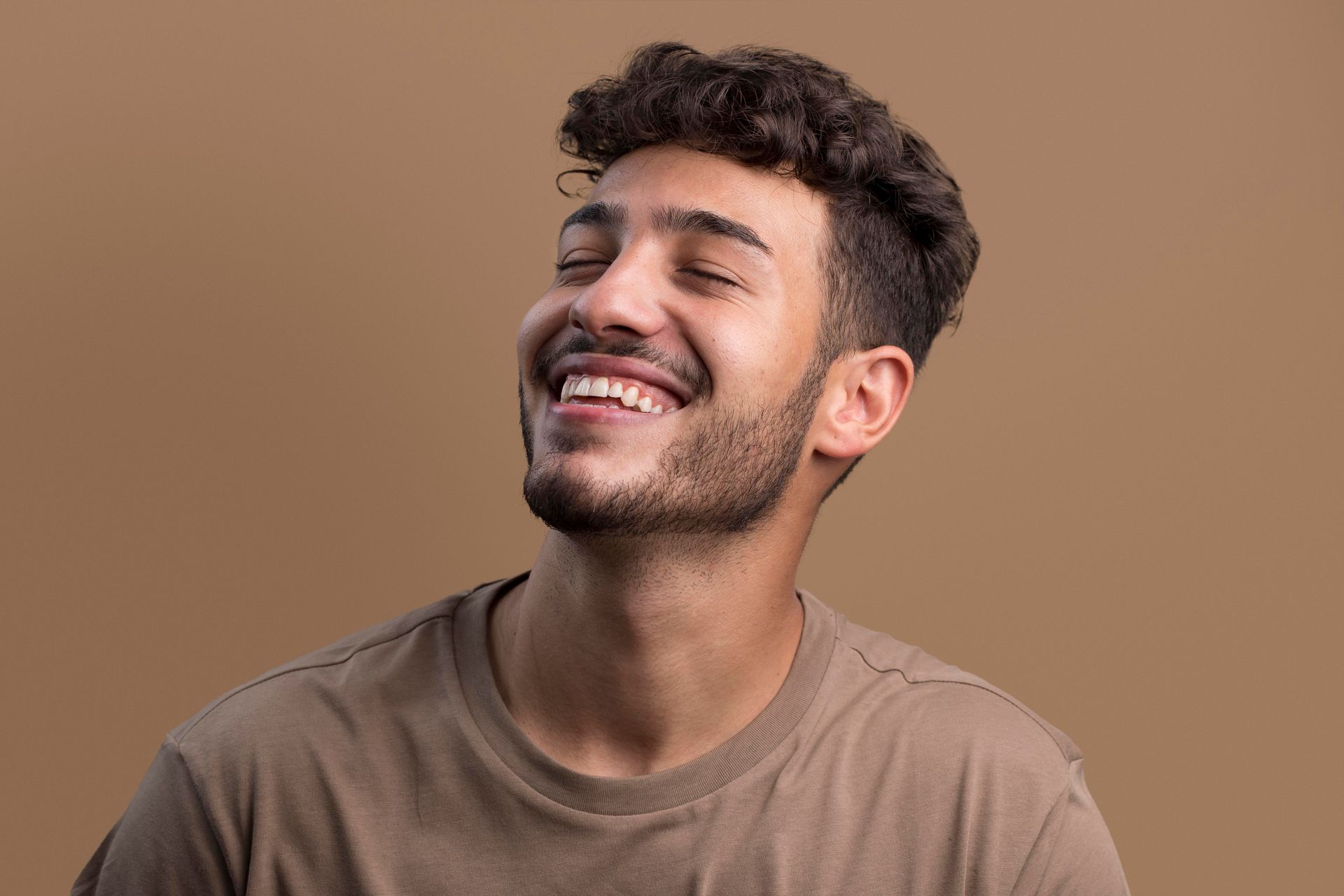 a man with a beard is laughing with his eyes closed