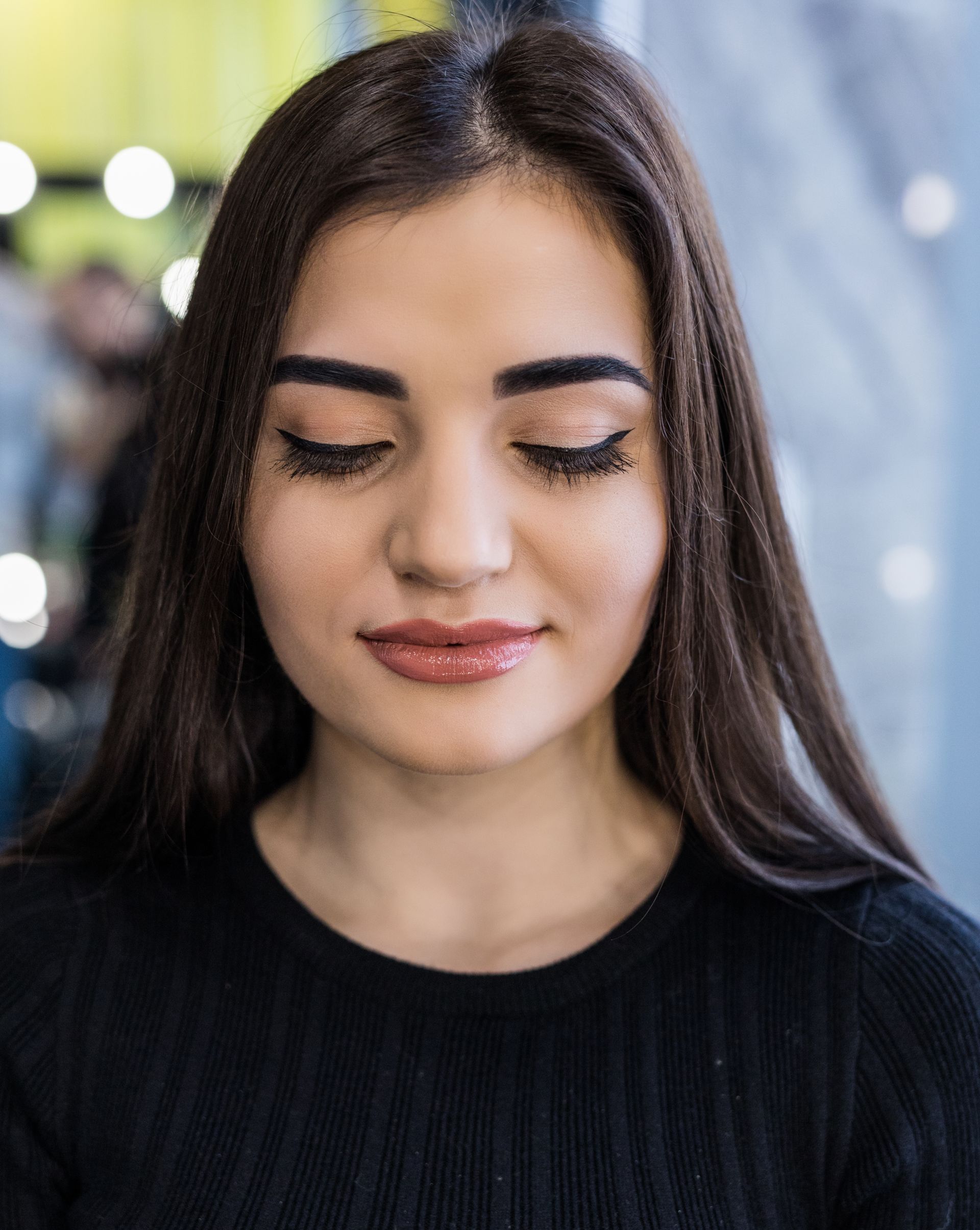 a woman with her eyes closed is wearing a black sweater