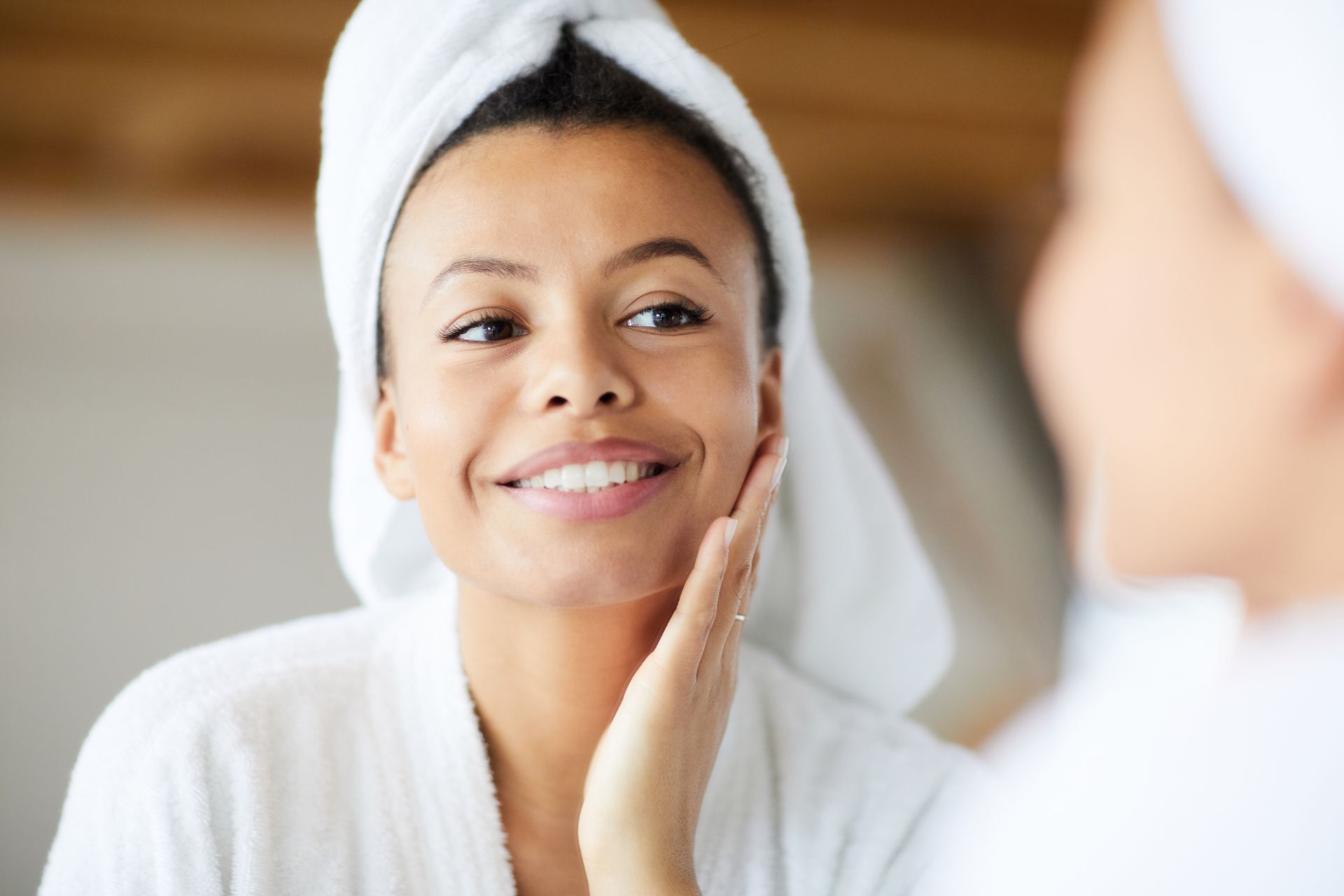 a woman with a towel wrapped around her head looks at herself in the mirror