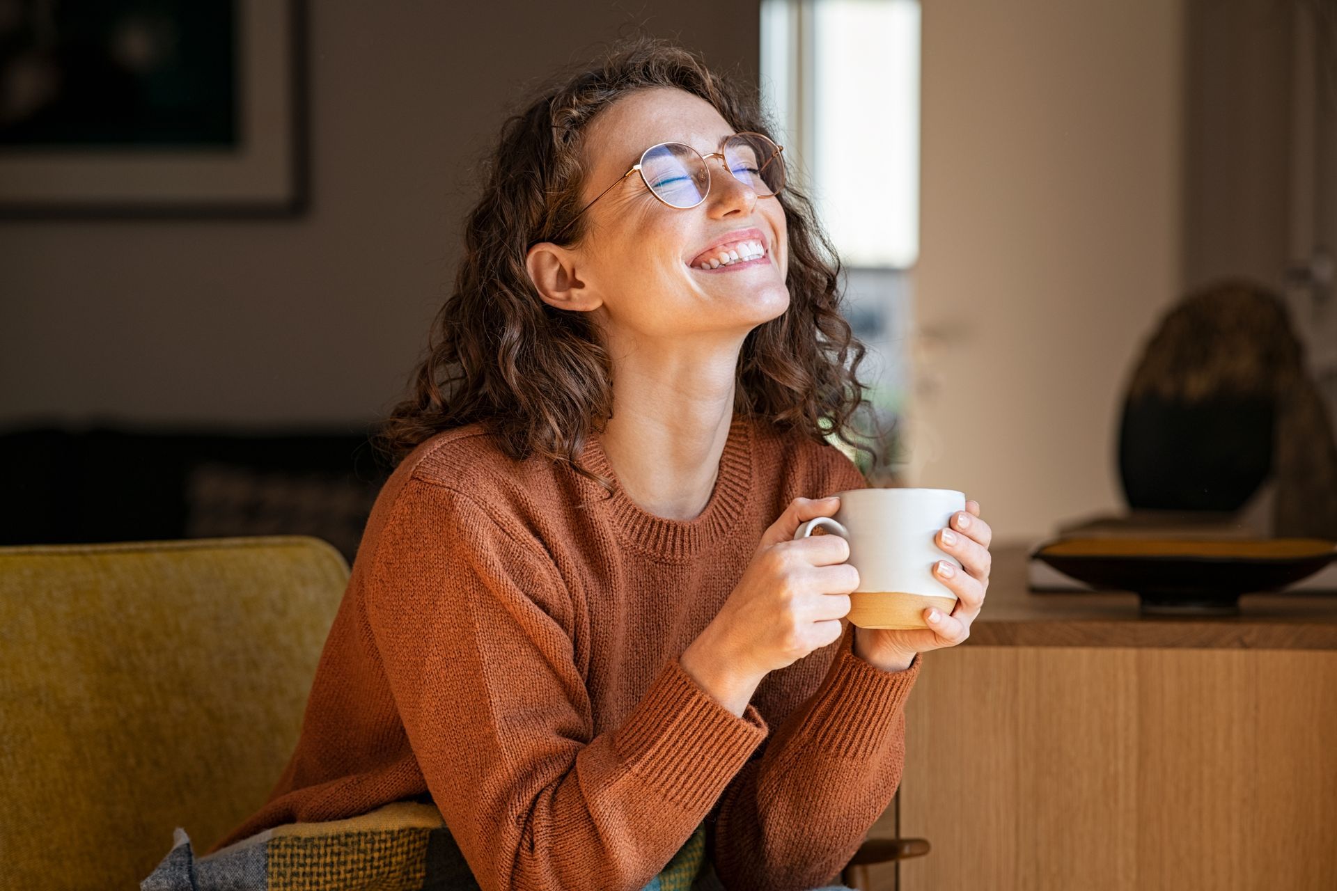 a woman wearing glasses is smiling while holding a cup of coffee