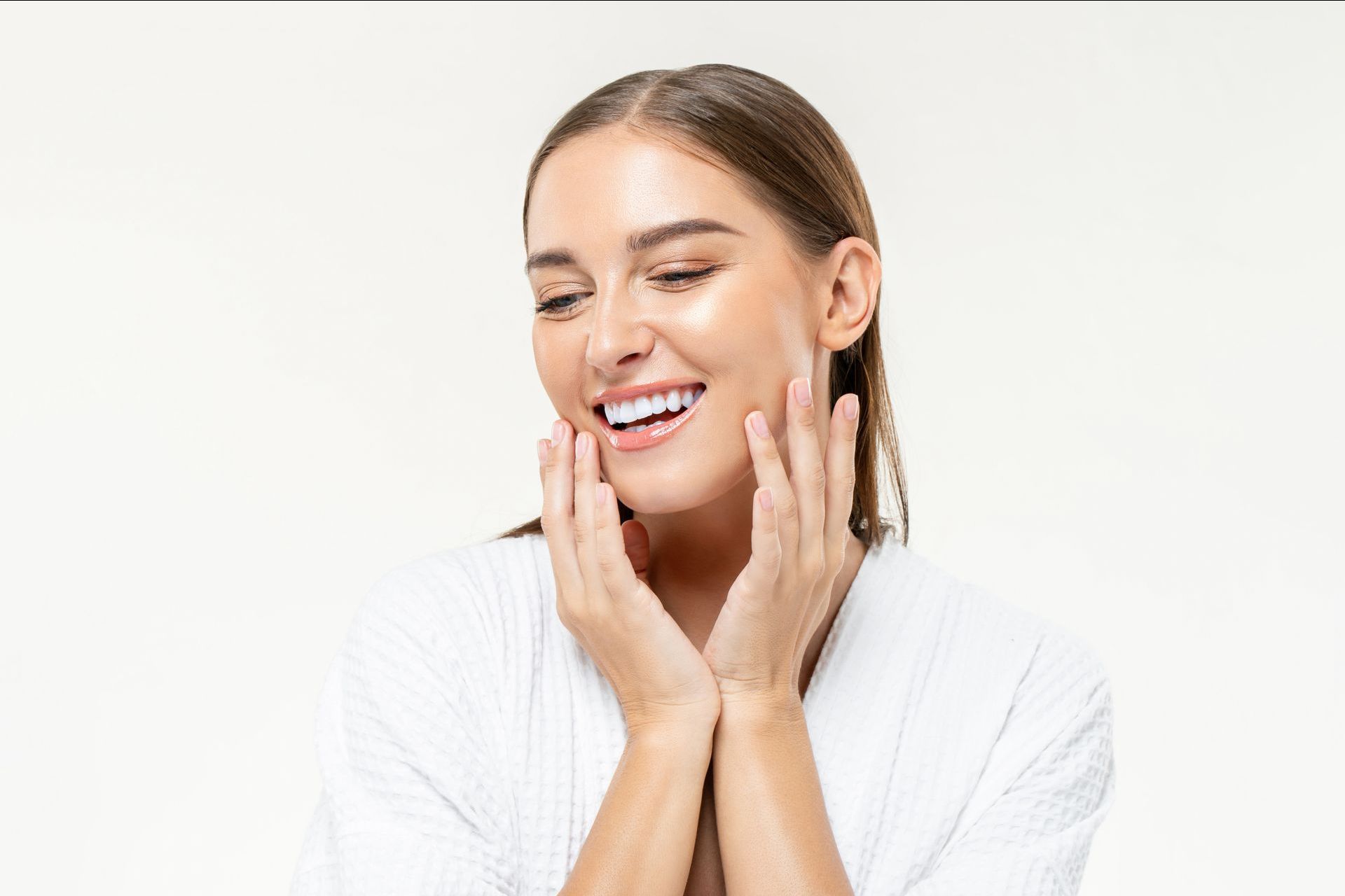 a woman in a white robe is smiling and touching her face