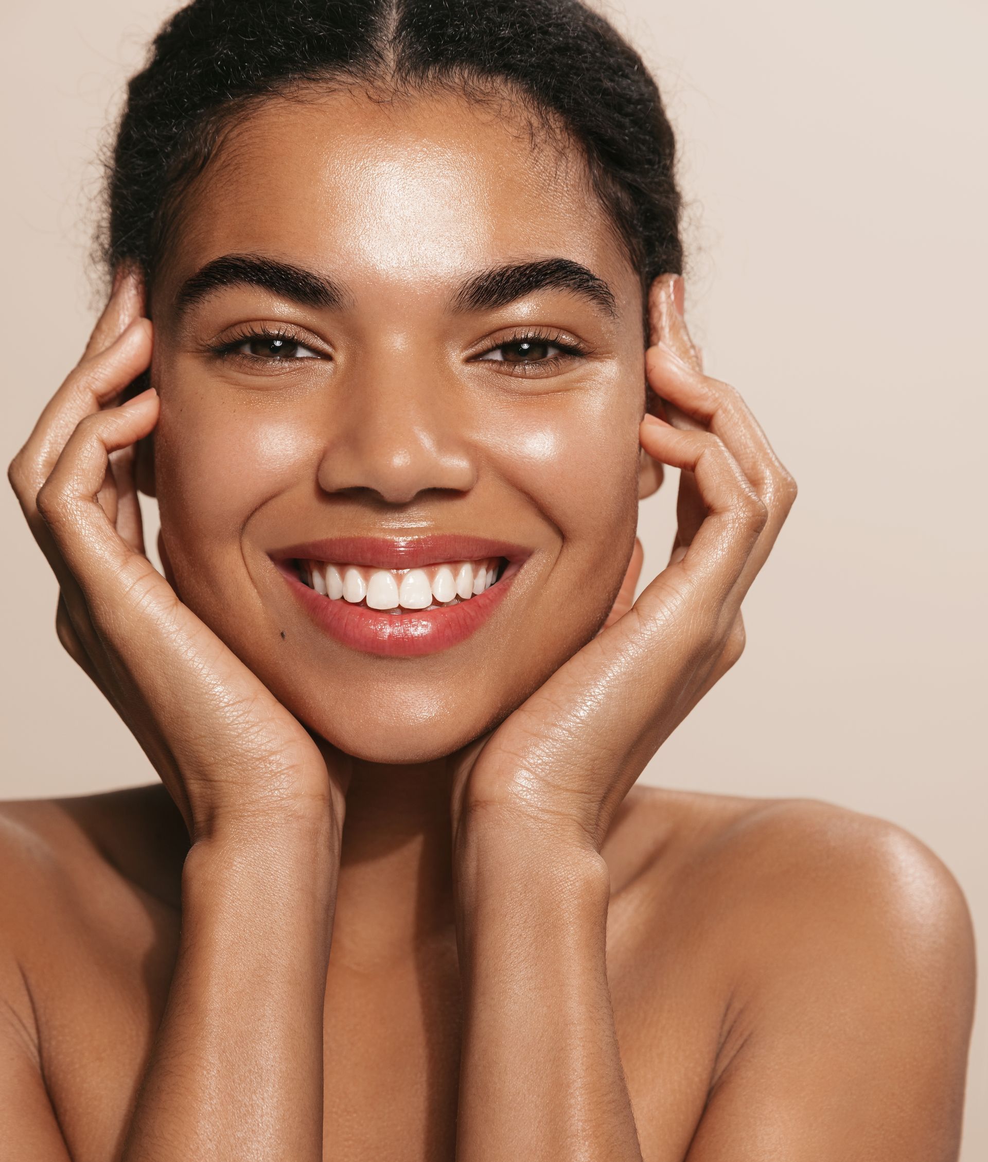 a woman is smiling and touching her face with her hands
