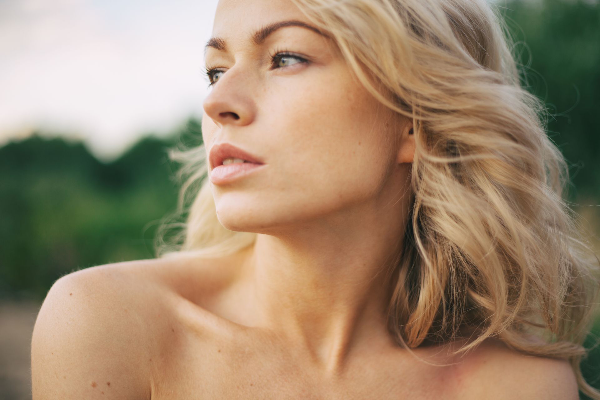 a close up of a woman 's face with her hair blowing in the wind