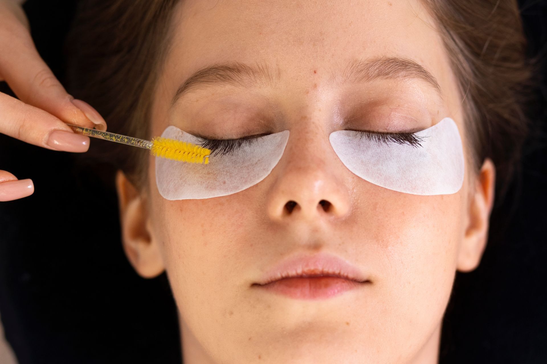 a woman getting her eyelashes done with a brush