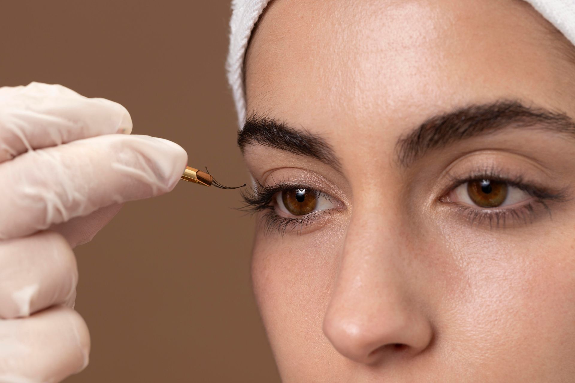 a woman with a towel on her head is getting her eyelashes done