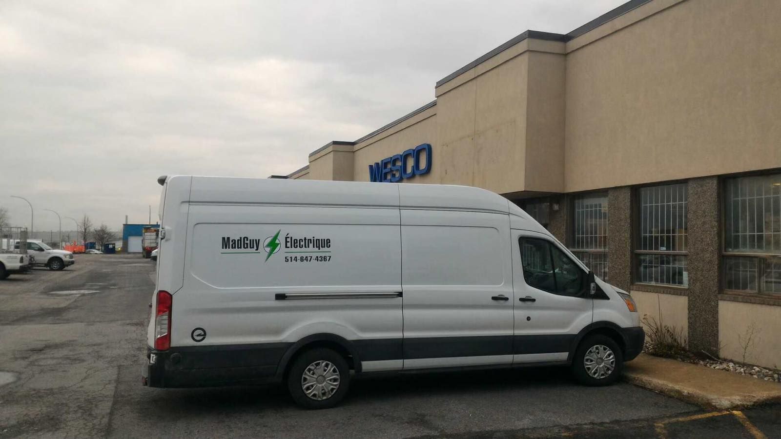 Une camionnette blanche garée devant une boutique beige par une journée grise