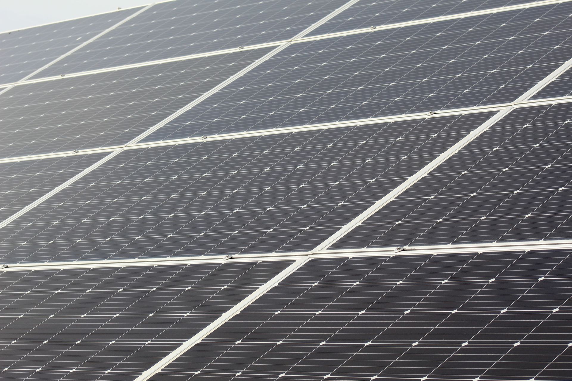 Une personne transporte un grand panneau solaire sur un toit en plein jour.