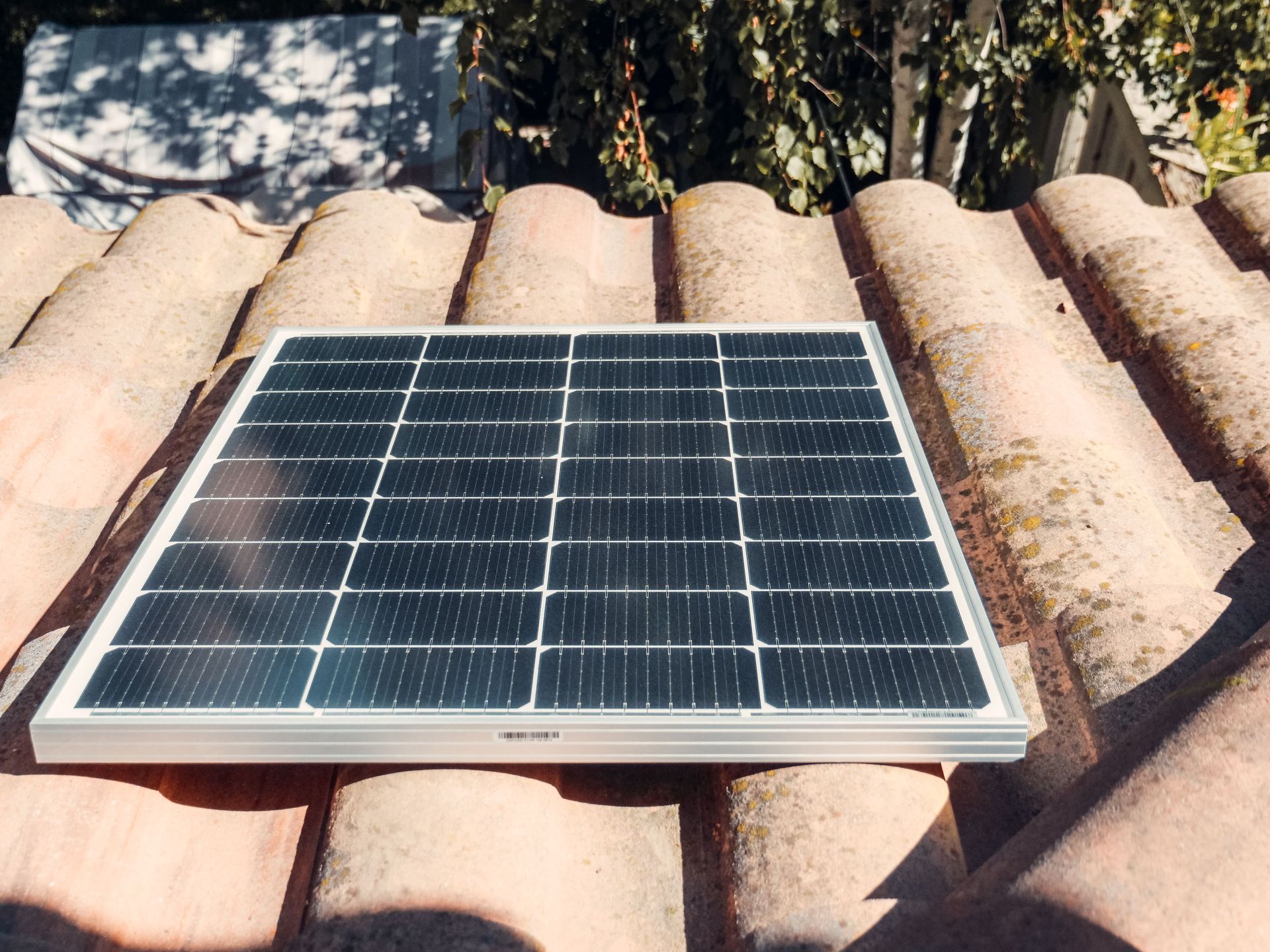 Personne tenant un panneau solaire à l'extérieur, portant des gants jaunes.