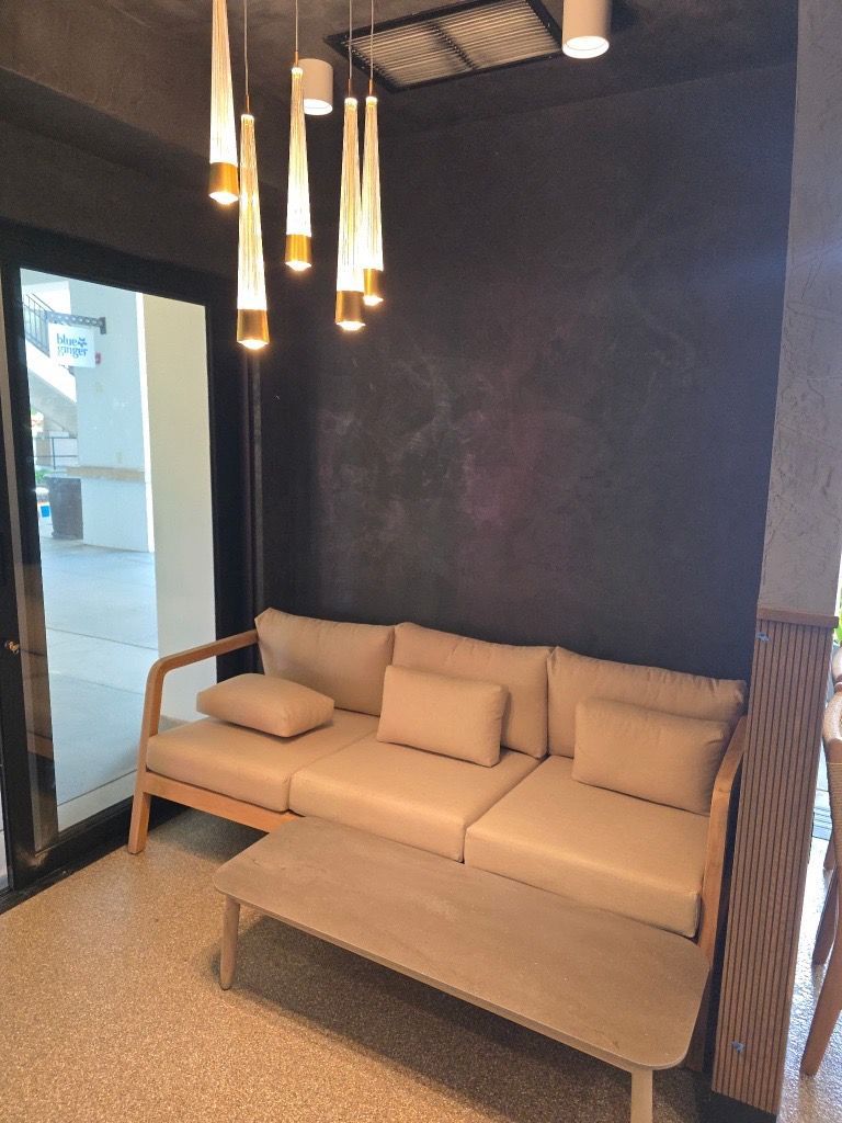 A modern seating area with a beige sofa, coffee table, and decorative hanging lights.