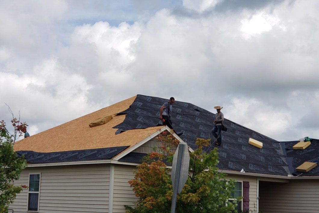 Two men are working on the roof of a house.